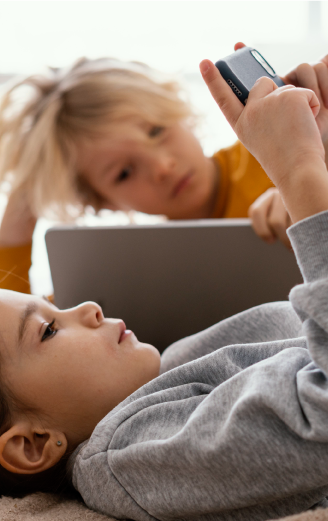 Zdjęcie - dwoje małych dzieci korzystających ze smartfona i laptopa.